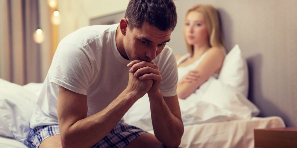 Erectile Dysfunction and sexual problems concept - upset man sitting on the bed with woman on the back
